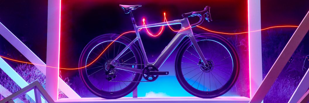 A dazzling image of Cervelo’s new Rouvida e-bike standing in a white frame as a red light-trail runs left to right and encircles the bike’s top tube.