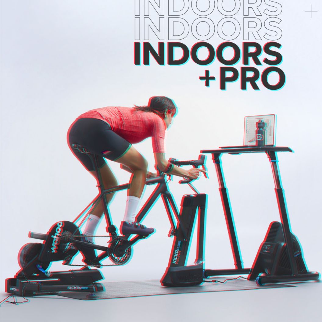 An RBG shift image of a rider training indoors on Wahoo’s ecosystem of indoor training tools including a fan, desk, wheel riser, and trainer. 