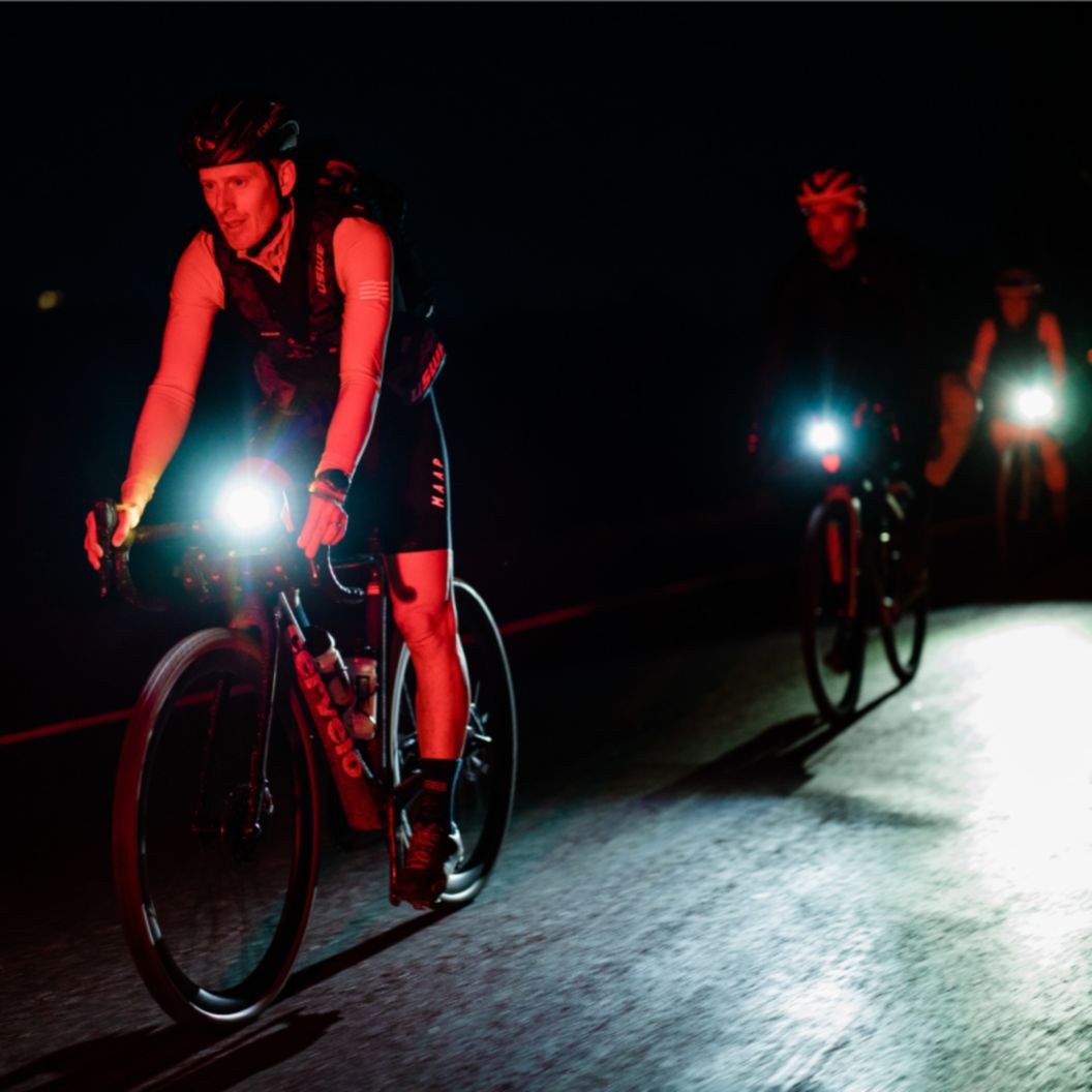 A cyclist rides their bike at night, while the front riding light is on. 
