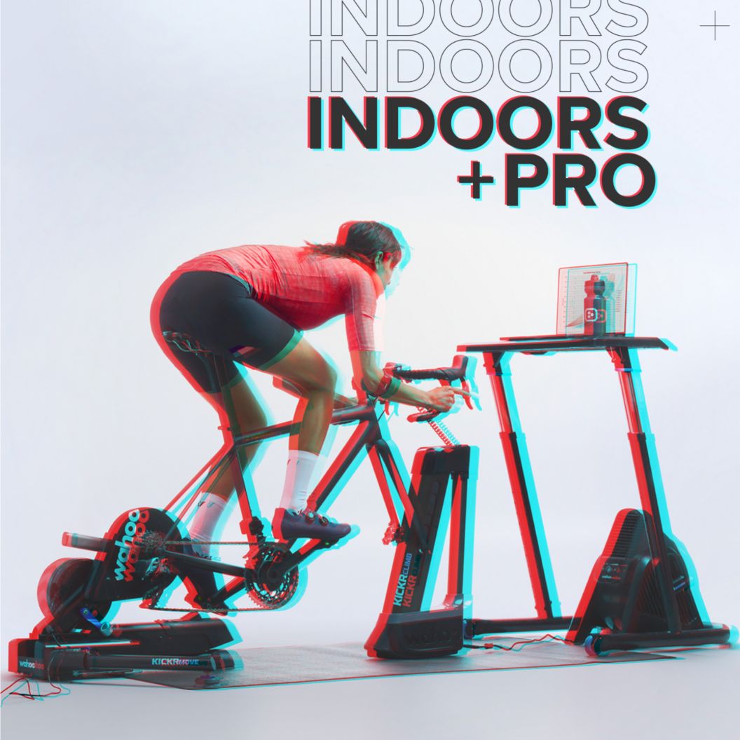 An RBG shift image of a rider training indoors on Wahoo’s ecosystem of indoor training tools including a fan, desk, wheel riser, and trainer.