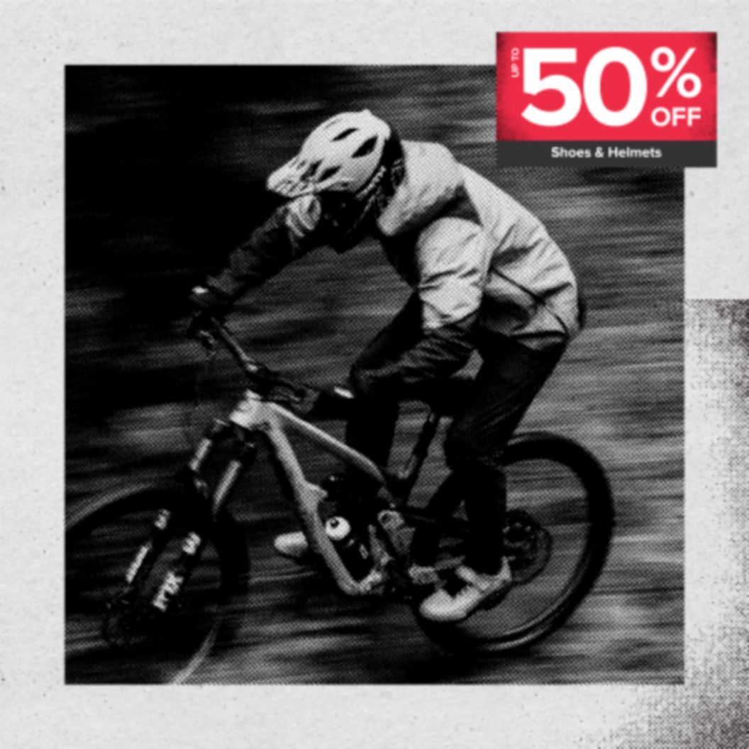 Up to 50% off shoes and helmets in a red box over a slow-shutter black and white image of an MTB rider at speed. 