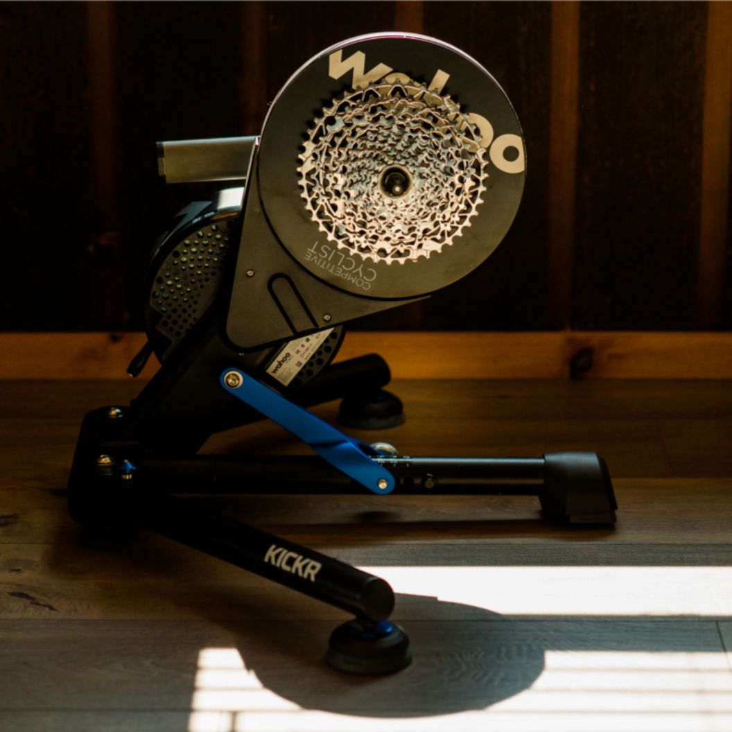 A Wahoo KICKR trainer sits on a floor in strong sun and shadow. 