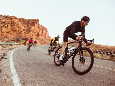 Road cyclists descend a turn in the desert. 