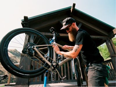 A person cleans a bike in a workstand.