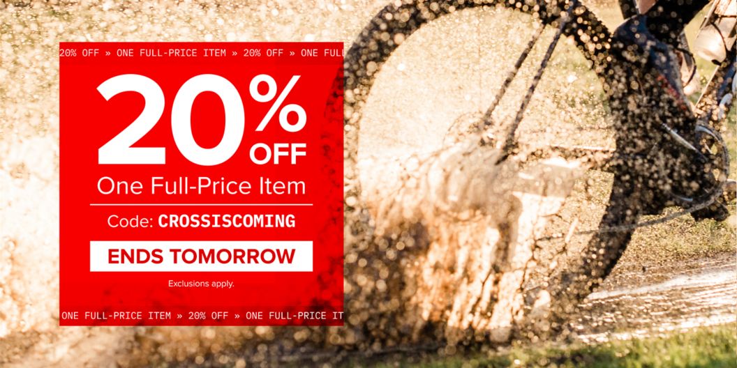 A red block with text reading “20% off one full-price item with code CROSSISCOMING, ends tomorrow, exclusions apply” is shown over a photo of a rider’s wheel going through a mud puddle. 