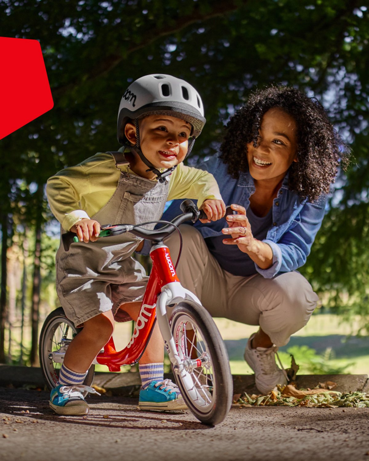 little kid riding balance bike with parent's help.