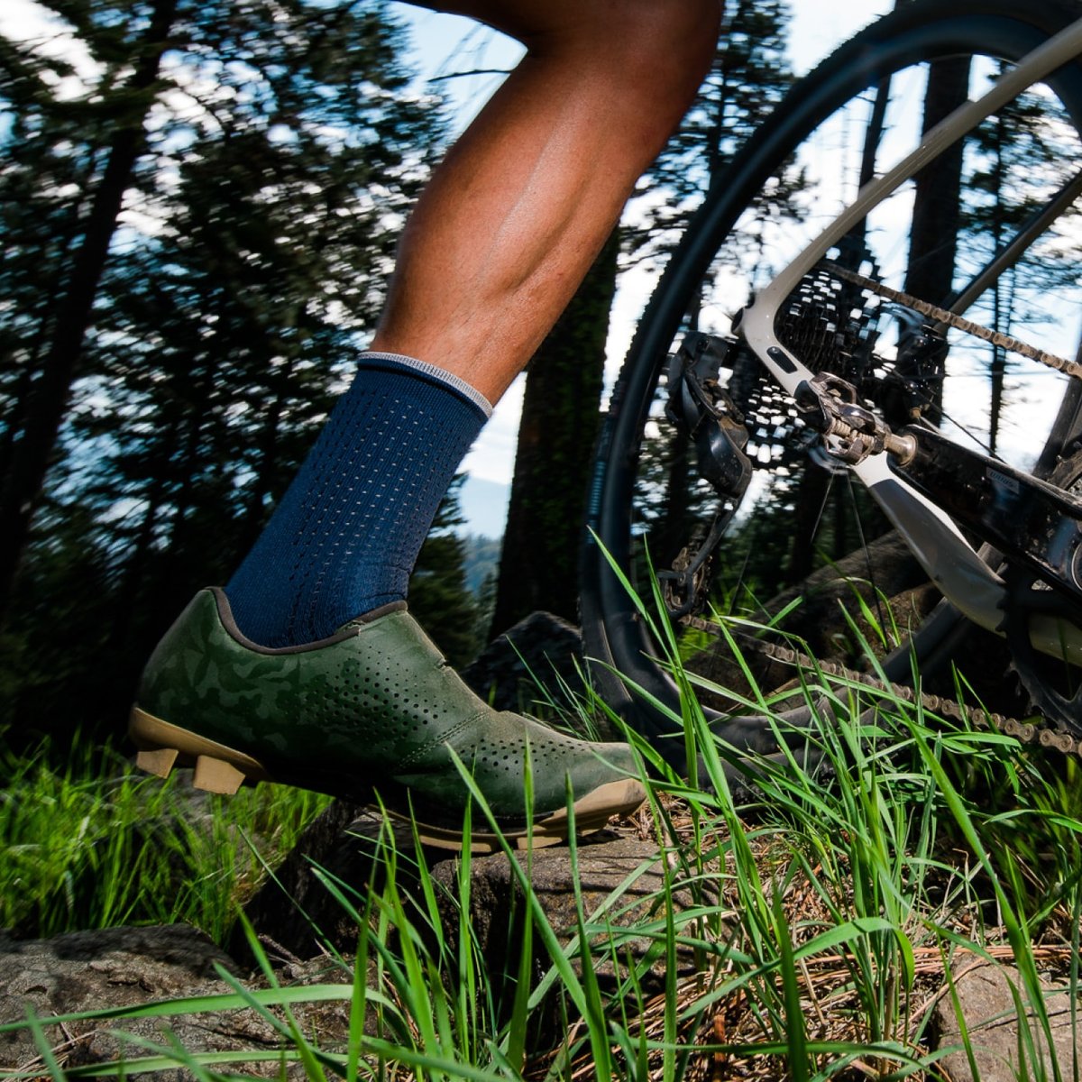 A gravel rider walks a bike in the forest. 