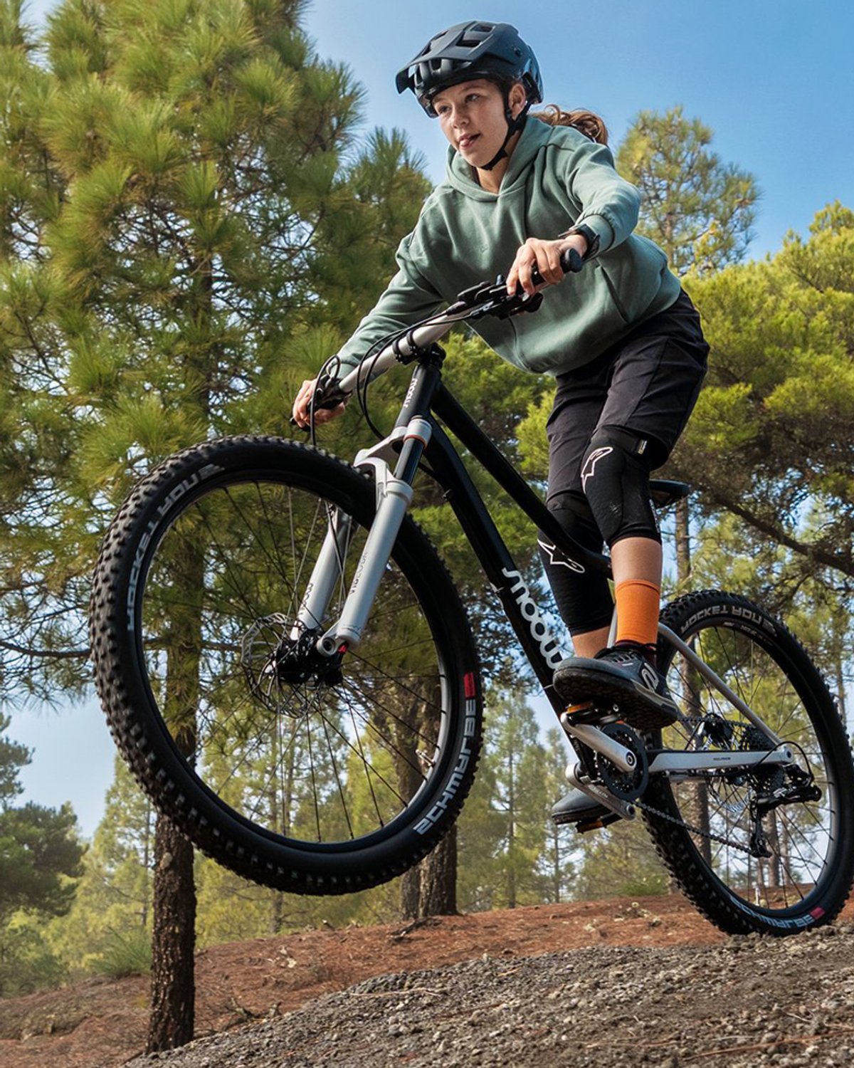 kid wearing helmet riding Woom Off mountainbike  and getting air off a dirt jump.