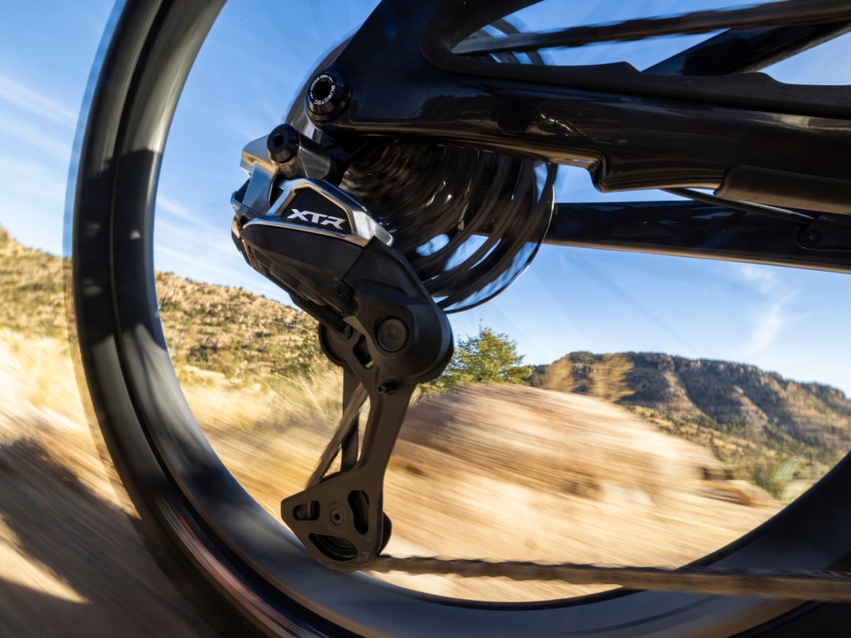 Closeup of a rear mountain bike wheel on the move. The XTR Di2’s derailleur is front and center.