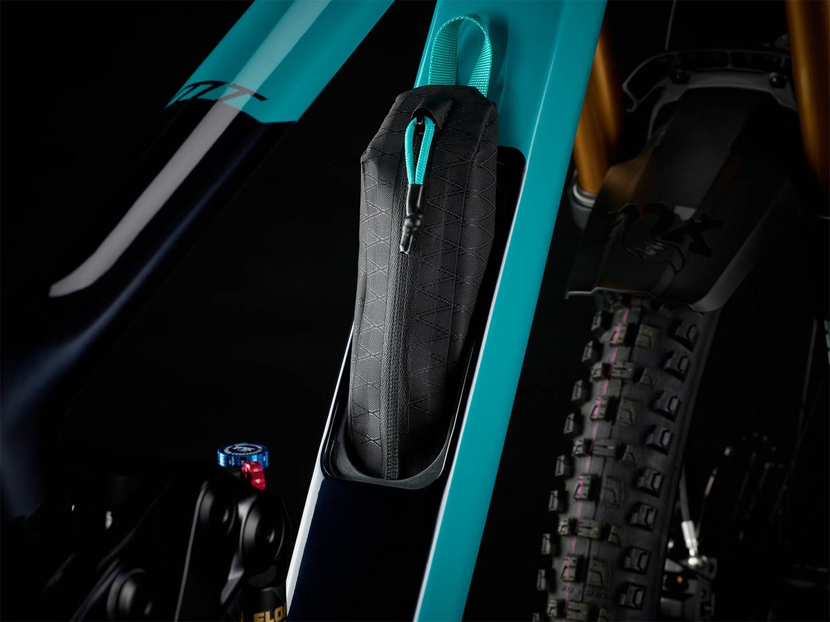 Zippered black tool pouch pulled from the in-frame storage cavity in the turquoise downtube of the Yeti MT.