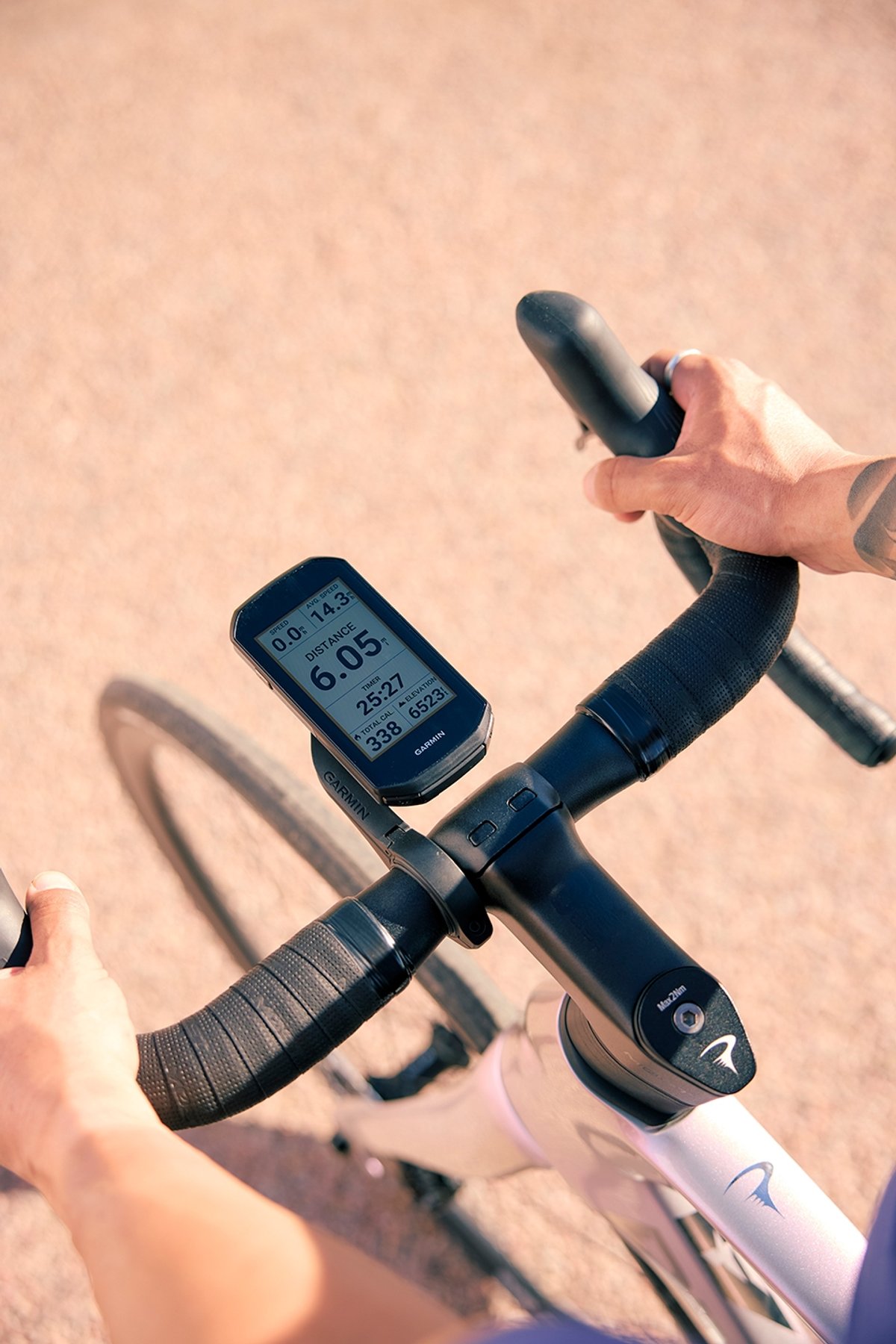 Road cyclist checking Garmin GPS cycling computer mounted on Pinarello road bike handlebar showing distance and elevation data