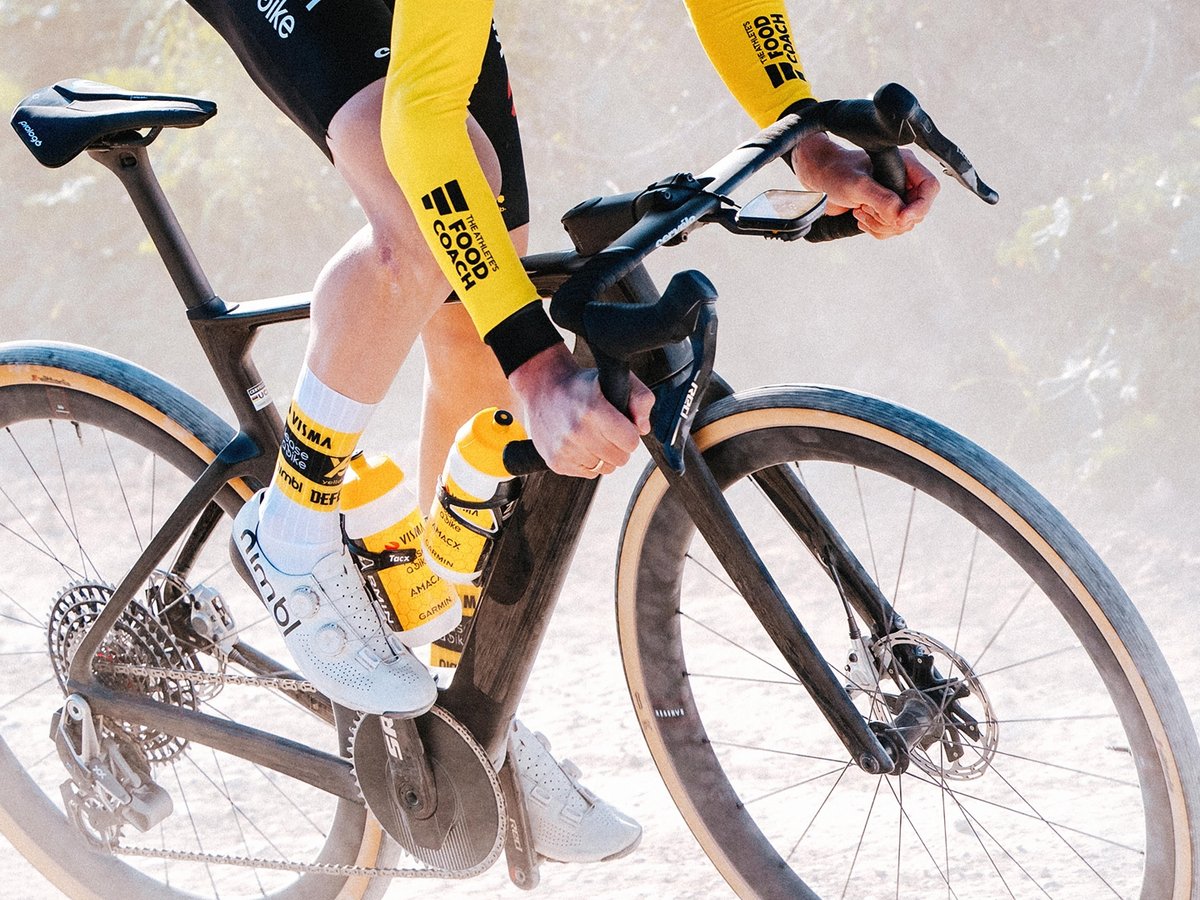 A gravel racer on a glossy black Aspero 5 charging out of the saddle. 