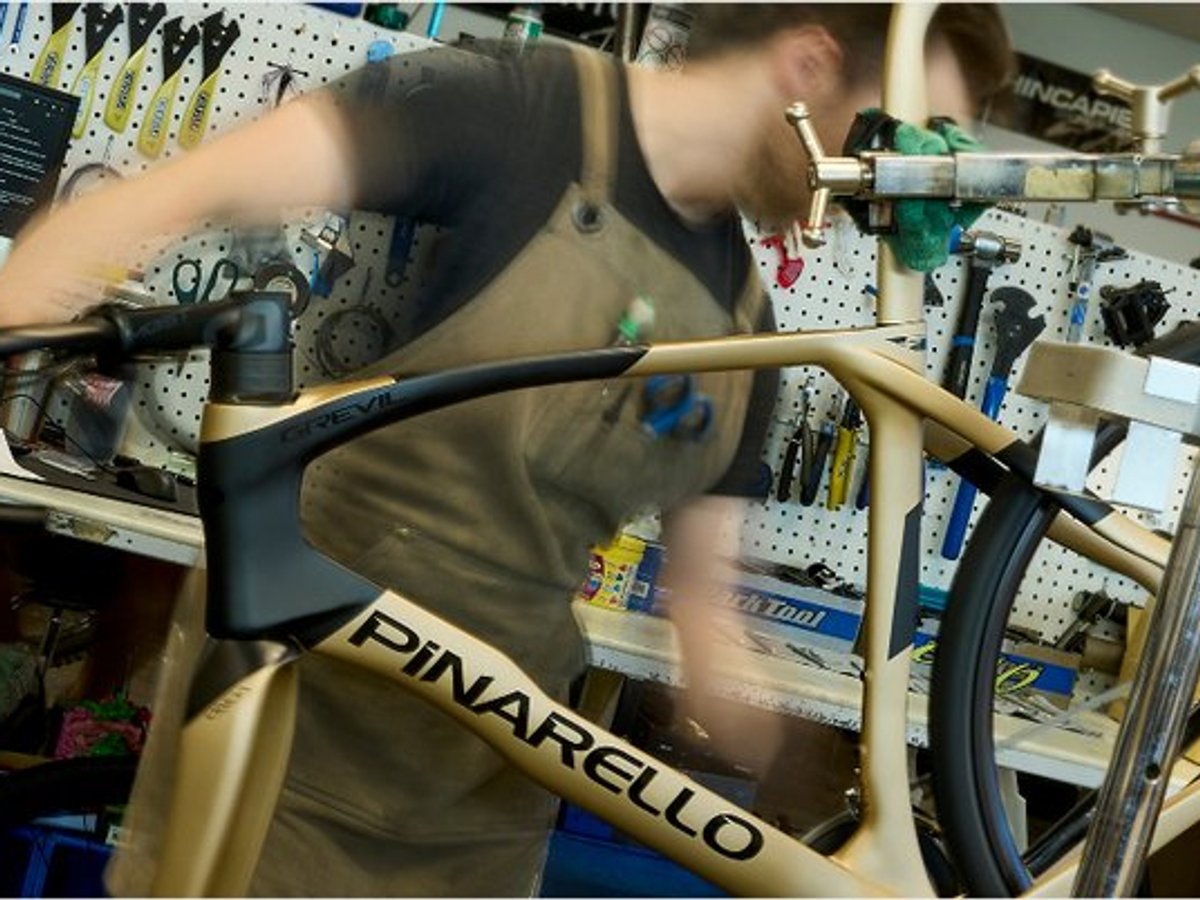 Bike technician building Pinarello road bike frame at fully equipped indoor cycling repair shop