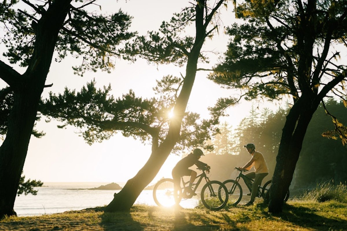 Two riders hanging out with their bikes at sunset.