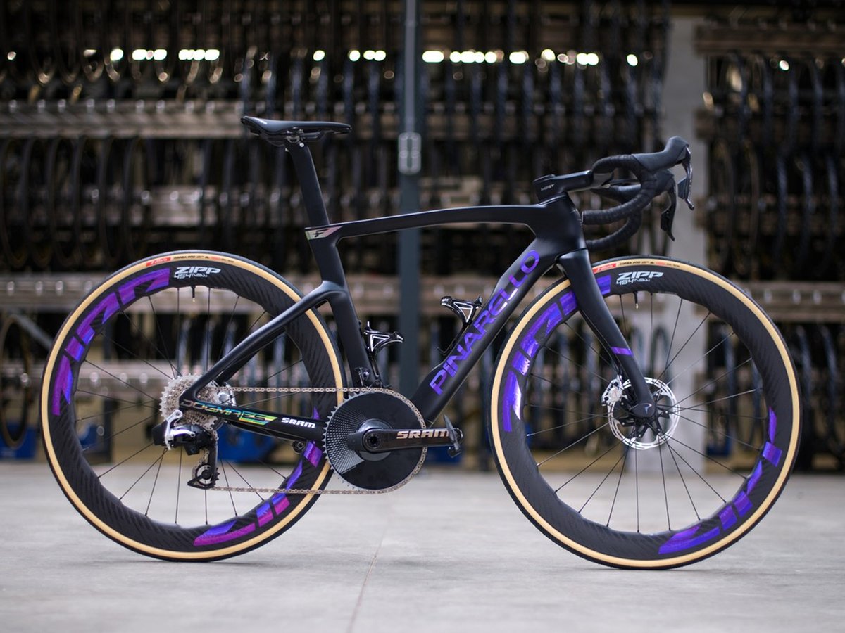 Pinarello Dogma F Edizione Speciale road bike in matte black with purple accents, SRAM groupset, and Zipp wheels, photographed in a bike factory setting.