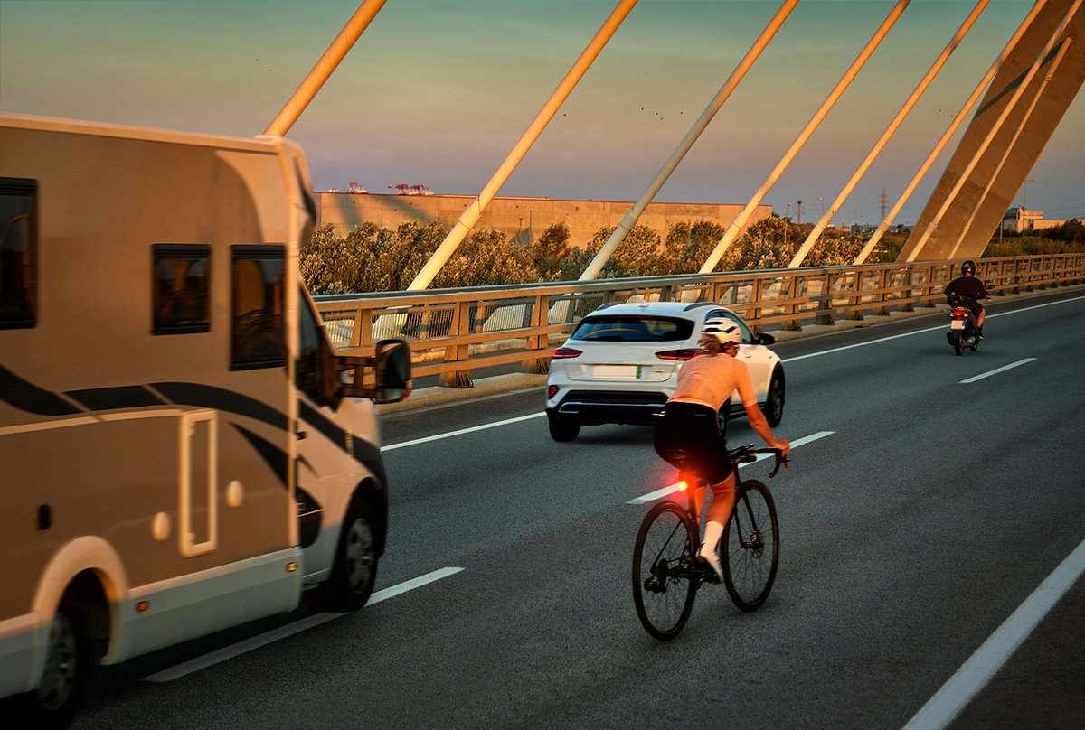 Road cyclist using high-visibility rear light on busy city bridge