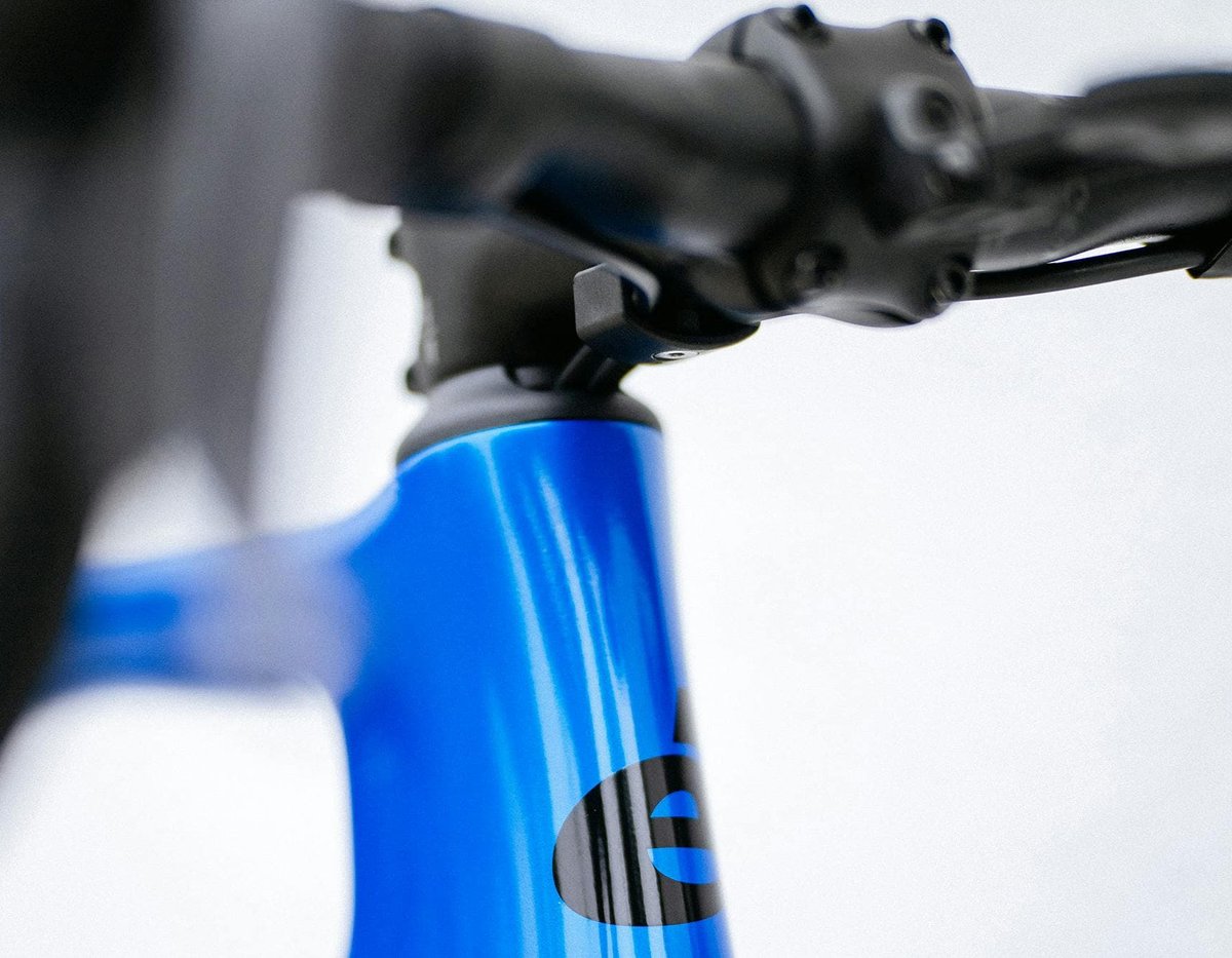 Close-up of Cervélo road bike head tube and stem junction showing blue carbon frame detail and road handlebar assembly