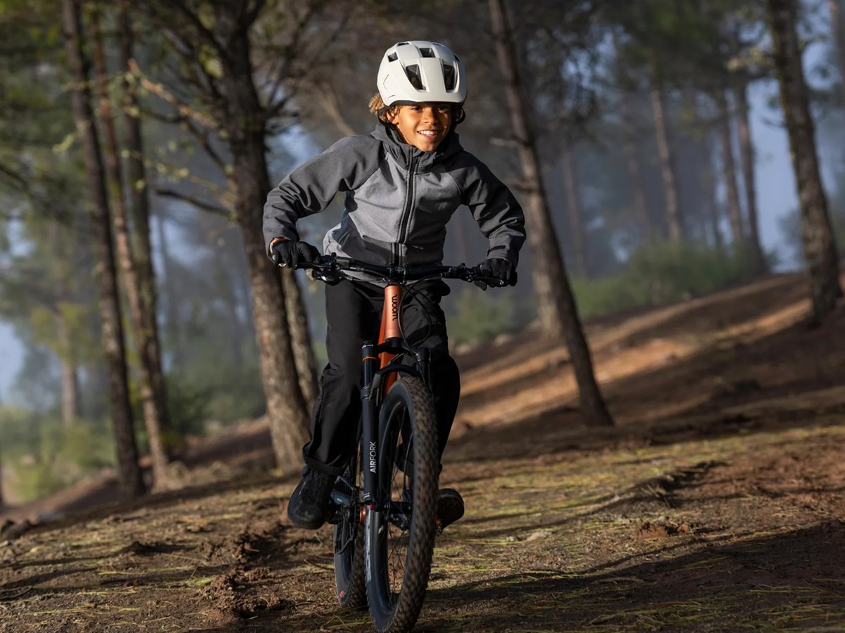 A child riding a dark woom mountain bike on a misty forest trail.