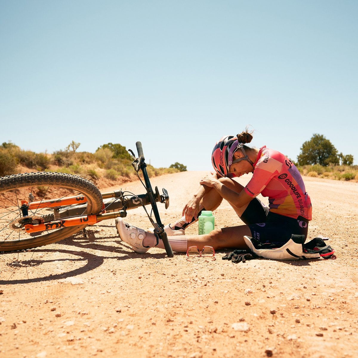 Sitting in the middle of a dirt road next to her Scott Spark bike, an exhausted Hannah Otto rests her forehead on her knee.