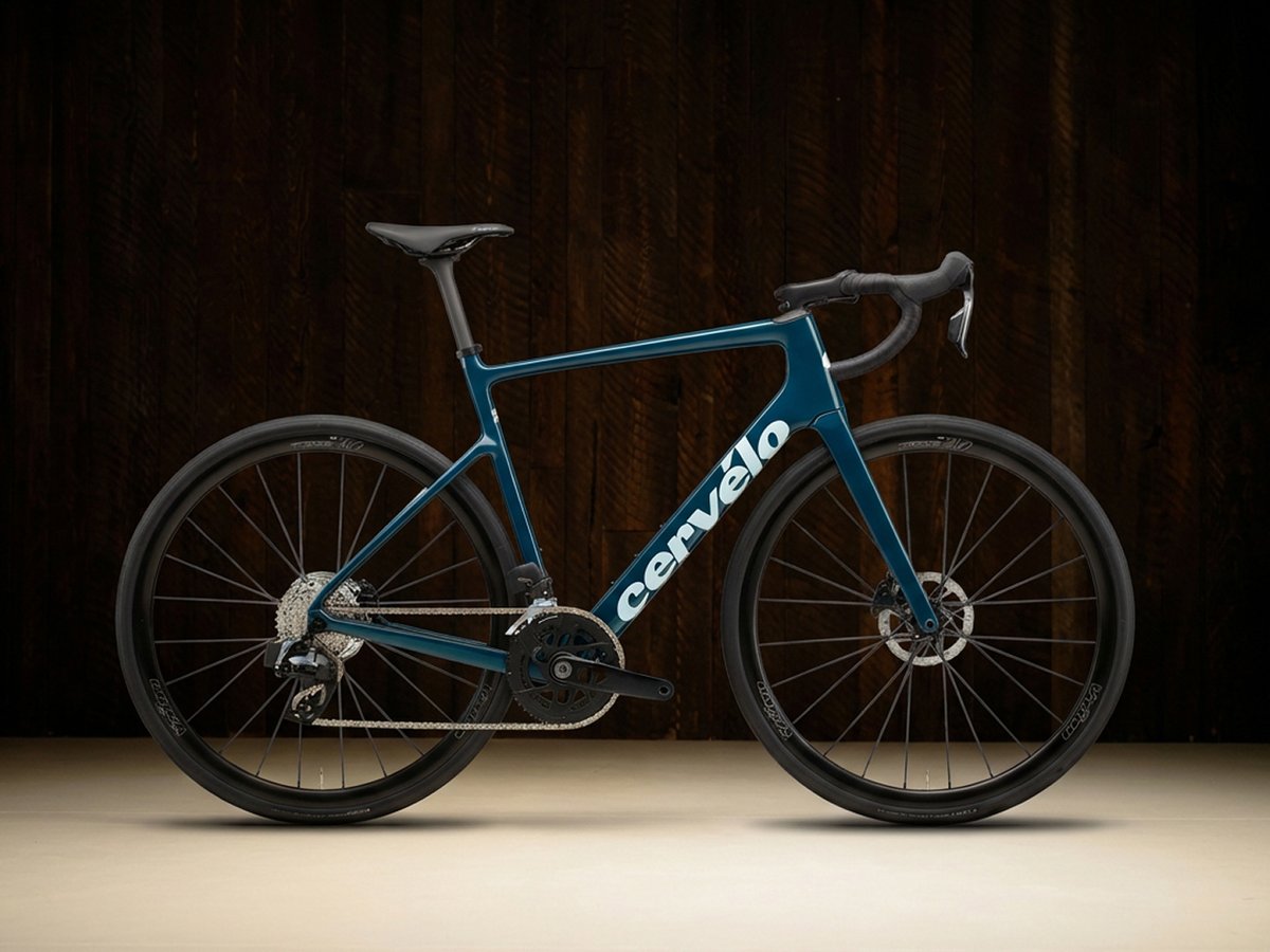 The Cervélo Caledonia road bike in deep teal with white logo lettering, shown in a side profile against a dark wood background.