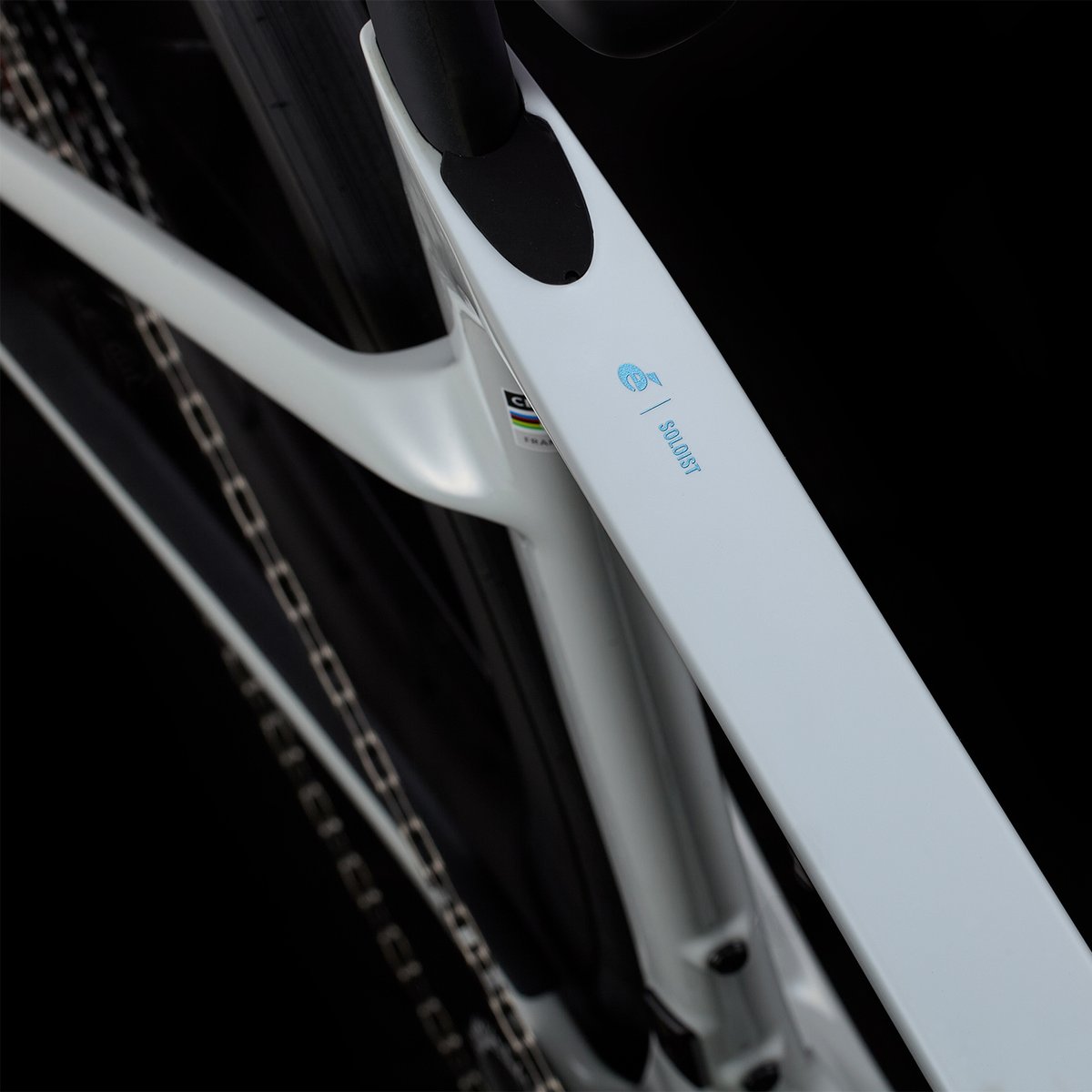 Close-up of the white Cervélo Soloist seat stay and bottom bracket area showing the blue Cervélo logo, Soloist model name, and UCI approval sticker, with chain visible.