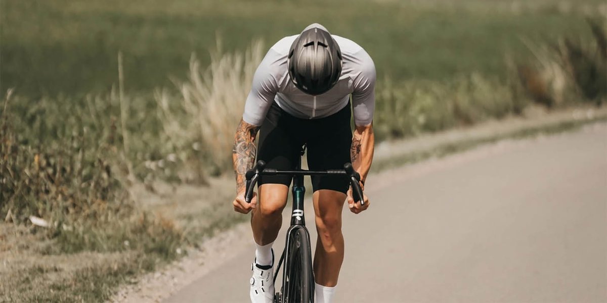 Cyclist pedaling hard down paved road on Ridley Falcn bike.