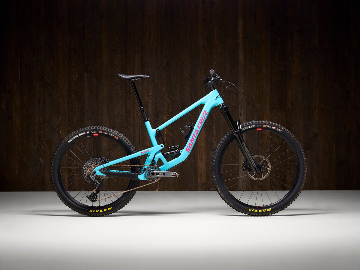 Santa Cruz Nomad mountain bike shown against a dark wood studio background.