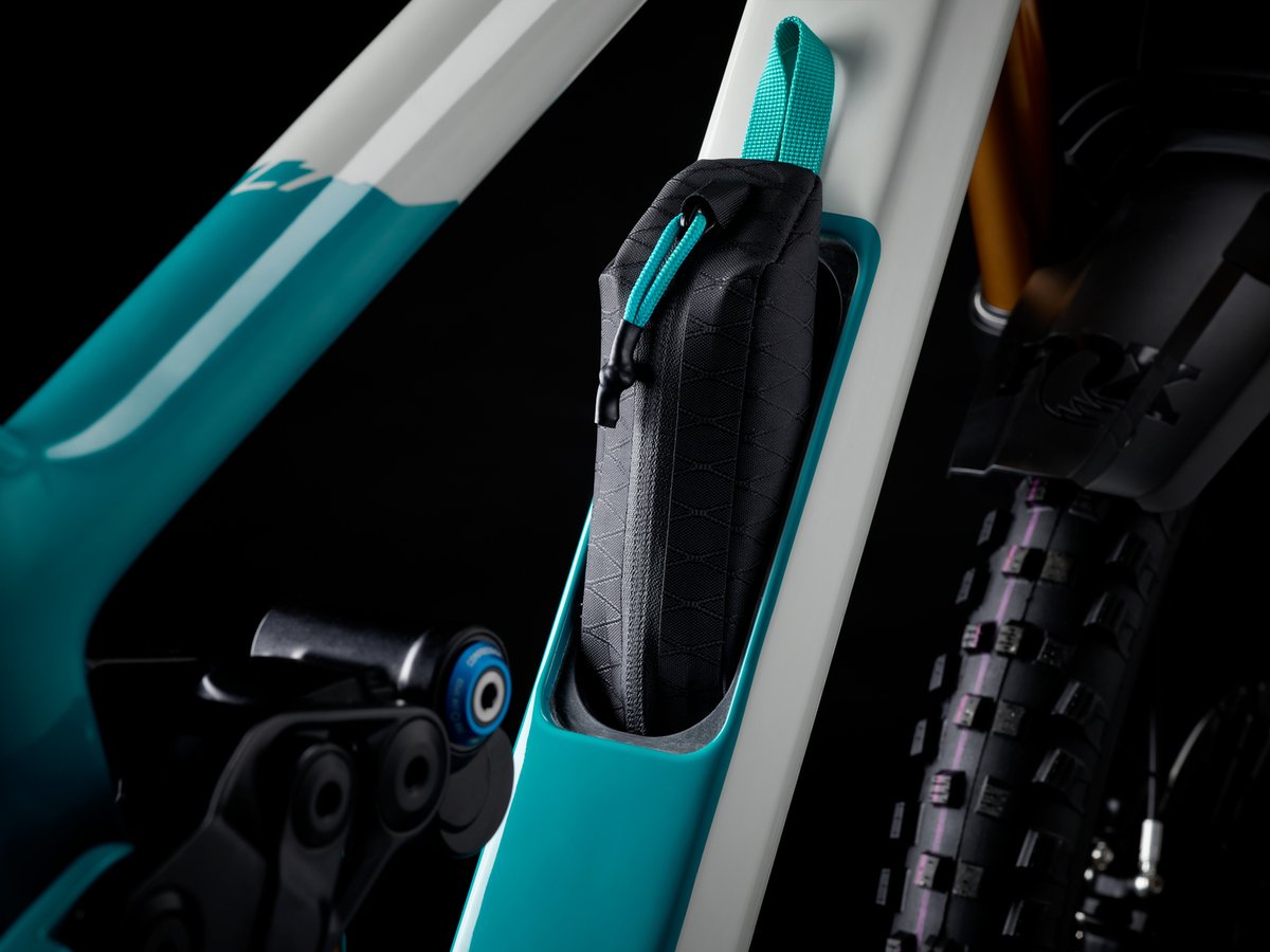 Down tube storage compartment with a black zippered accessory bag and teal pull-tab, tucked into the frame cutout.