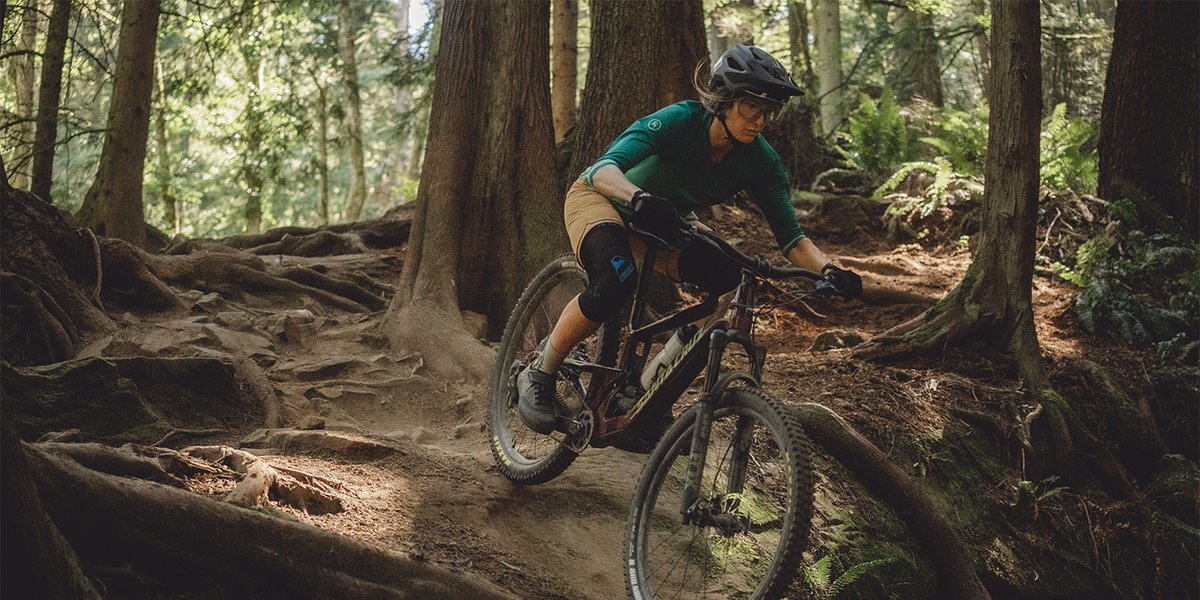 Mountain biker riding down a root covered trail.