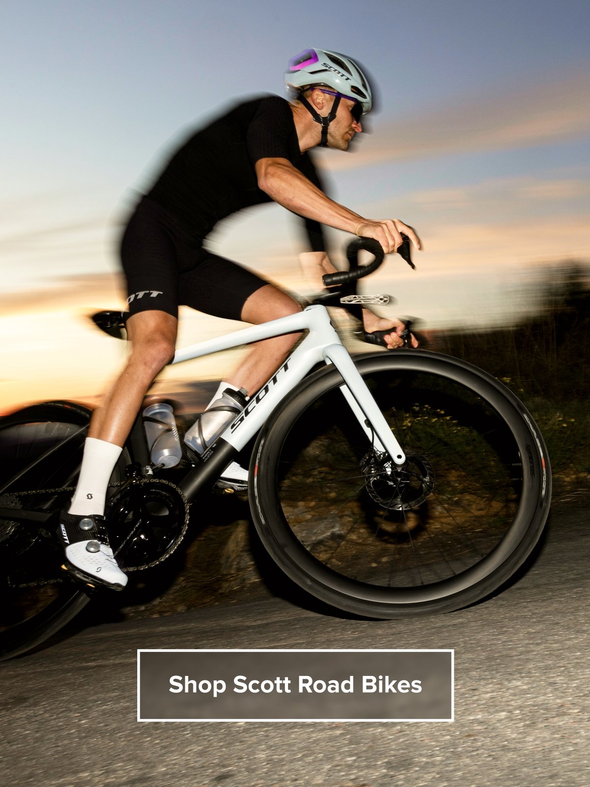 A cyclist rides at dusk Text overlay reads: Shop Scott Road Bikes