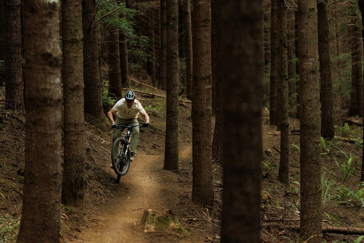 Rider racing down a dirt single track in the forest.