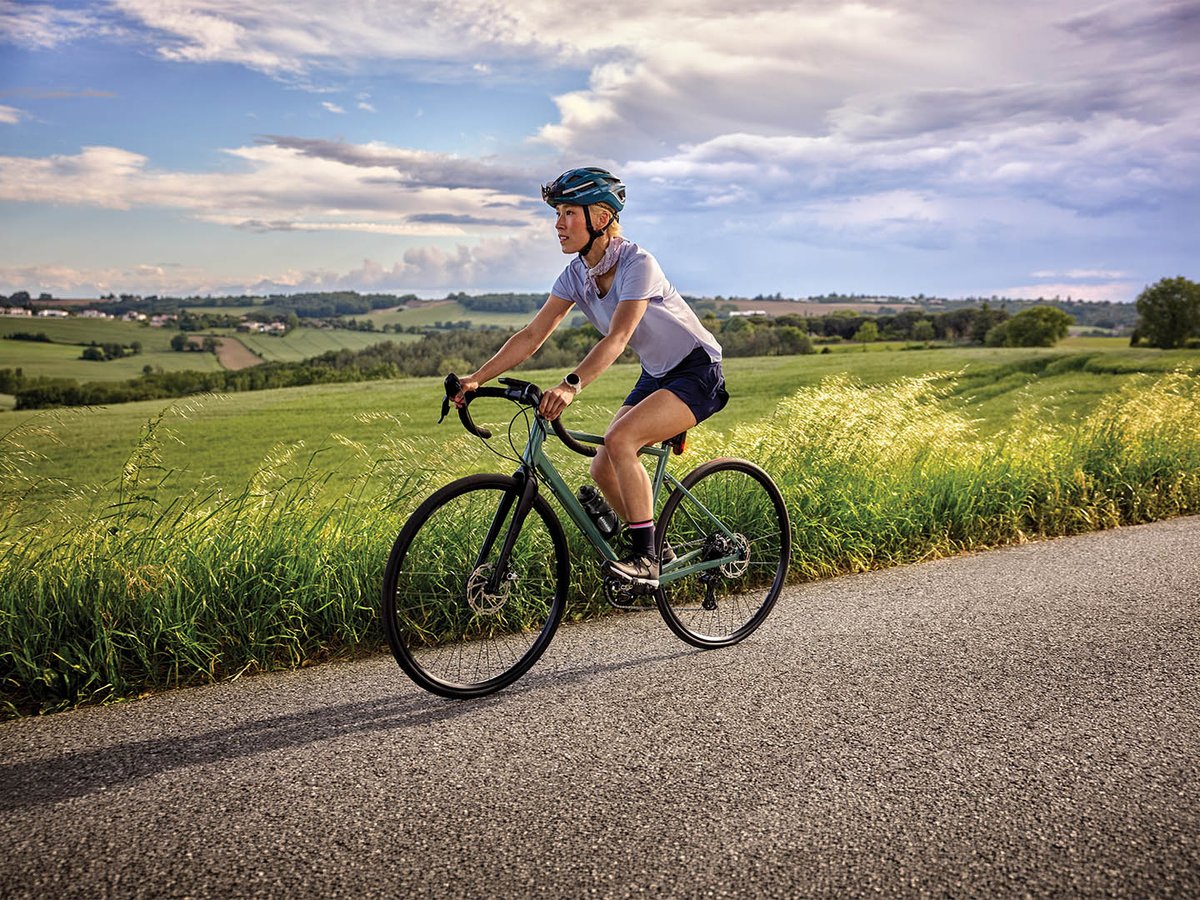 Cyclist on a country road through green fields
