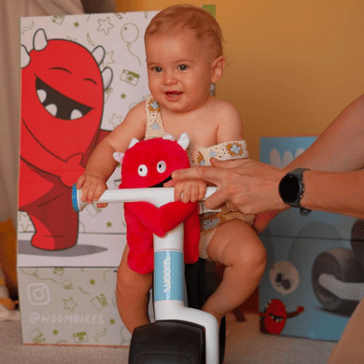 Baby being held up while hodling onto Wow bike.