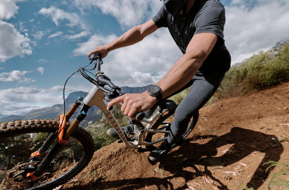 Person riding mountain bike wearing Garmin Fenix 9 watch.