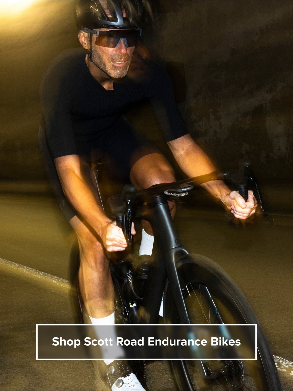 A cyclist rides with a smile. Text overlay reads: Shop Scott Road Endurance Bikes
