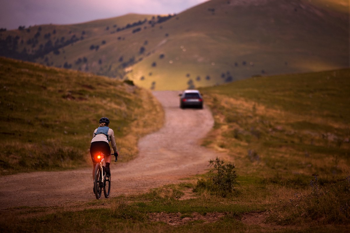 Cyclist riding at dusk with bright rear bike light for visibility