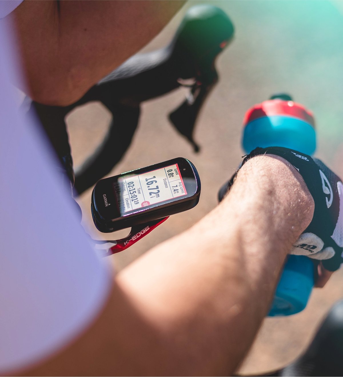 A Garmin bike computer mounted on road bike, seen through a cyclist’s arms as he rests one the handlebar.