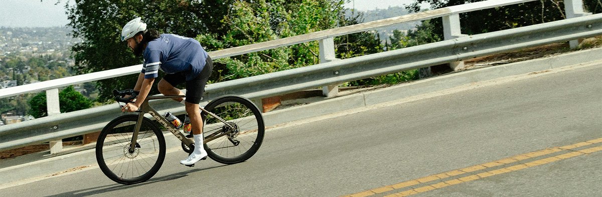 Person riding down a hill on a paved road on Caledonia bike.