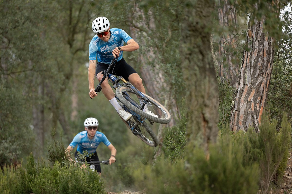 Rider sending the Pivot Mach 4 SL cross-country mountain bike on forest singletrack.