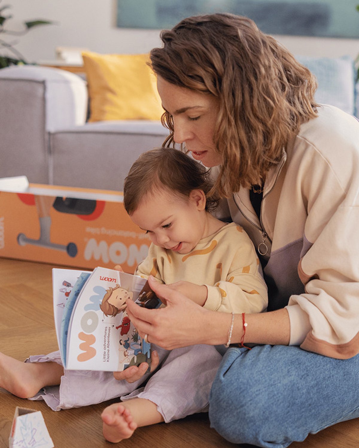parent and toddler sitting intheir lap looking at the included Woom Wow activity book.