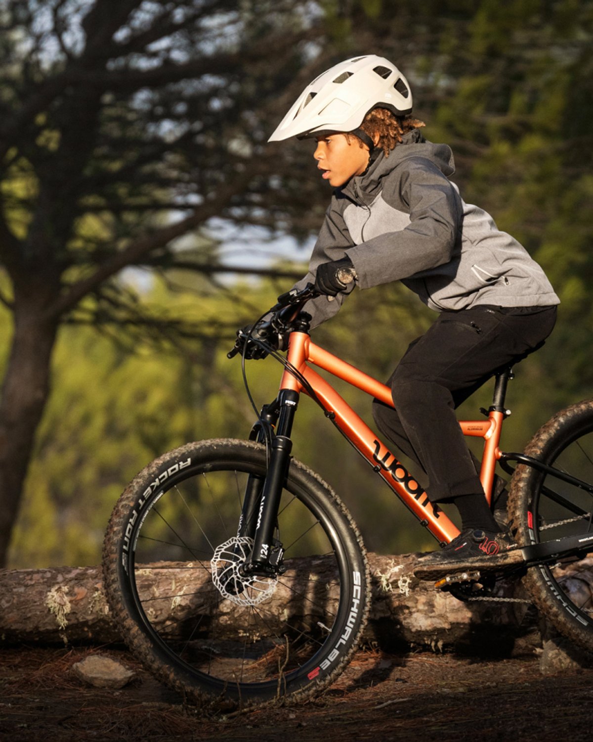 kid wearing helmet biking on dirt single track in the forest.
