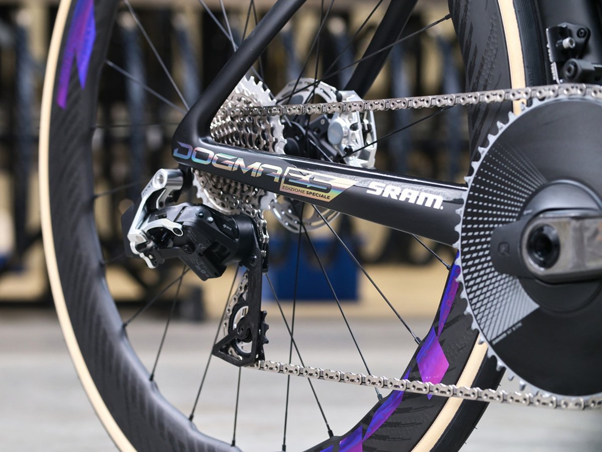 Close-up of the Pinarello Dogma F Edizione Speciale drivetrain showcasing the SRAM groupset, rear derailleur, and iridescent chainstay decal detail against a carbon deep-section rear wheel.
