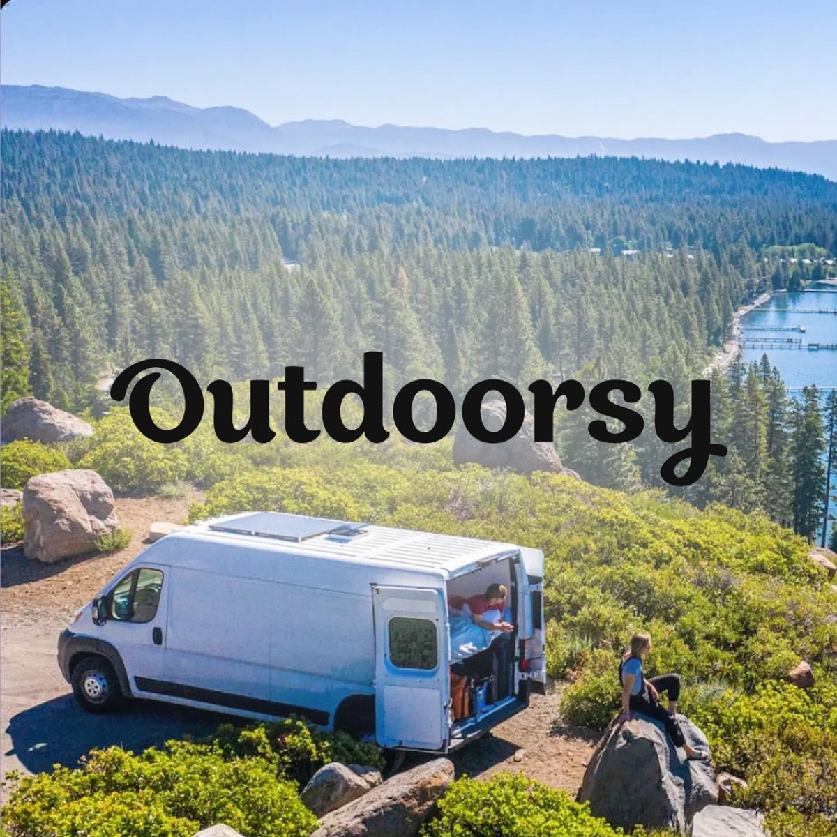 Outdoorsy logo over aerial view of a camper van parked on a rocky overlook above a pine forest and lakeside marina.