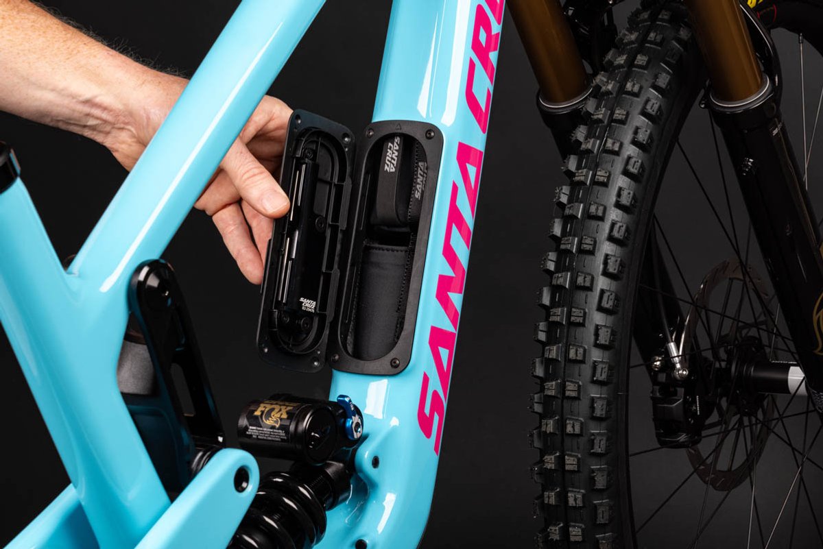 Hand accessing built-in frame storage glovebox on Santa Cruz Nomad full-suspension enduro mountain bike downtube
