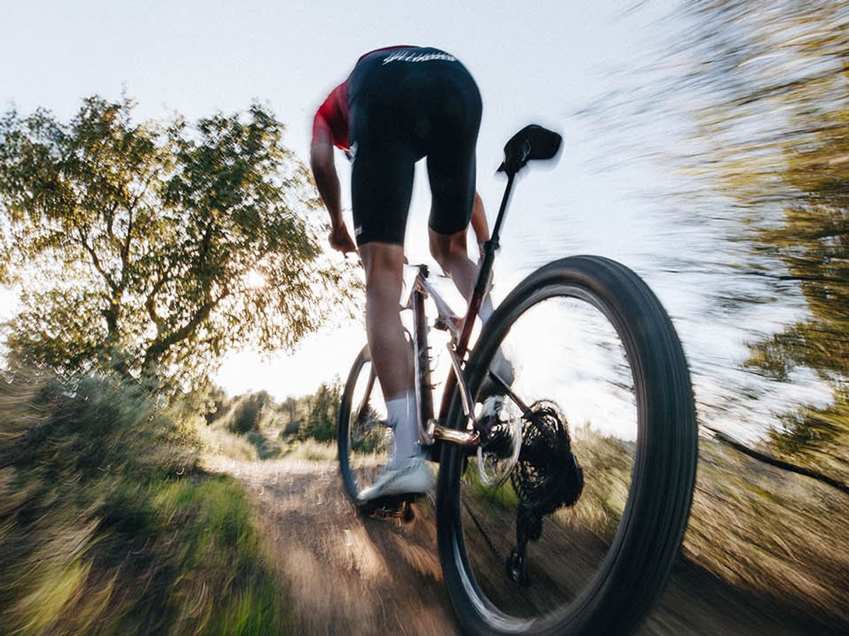XC cyclist riding fast uphill on hilly trail.