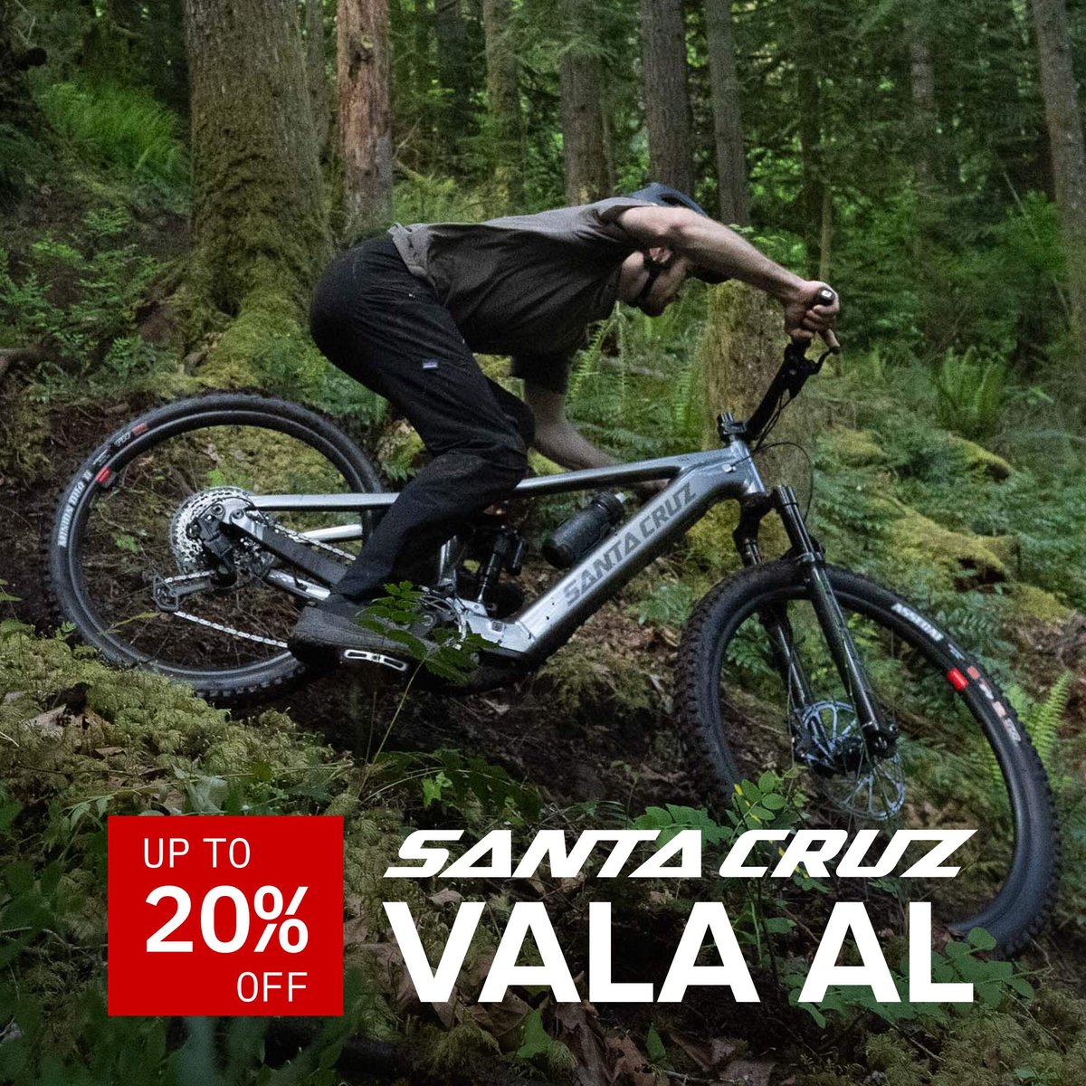Rider descending a technical forested trail on a Santa Cruz Vala AL electric mountain bike. Up to 20% off.