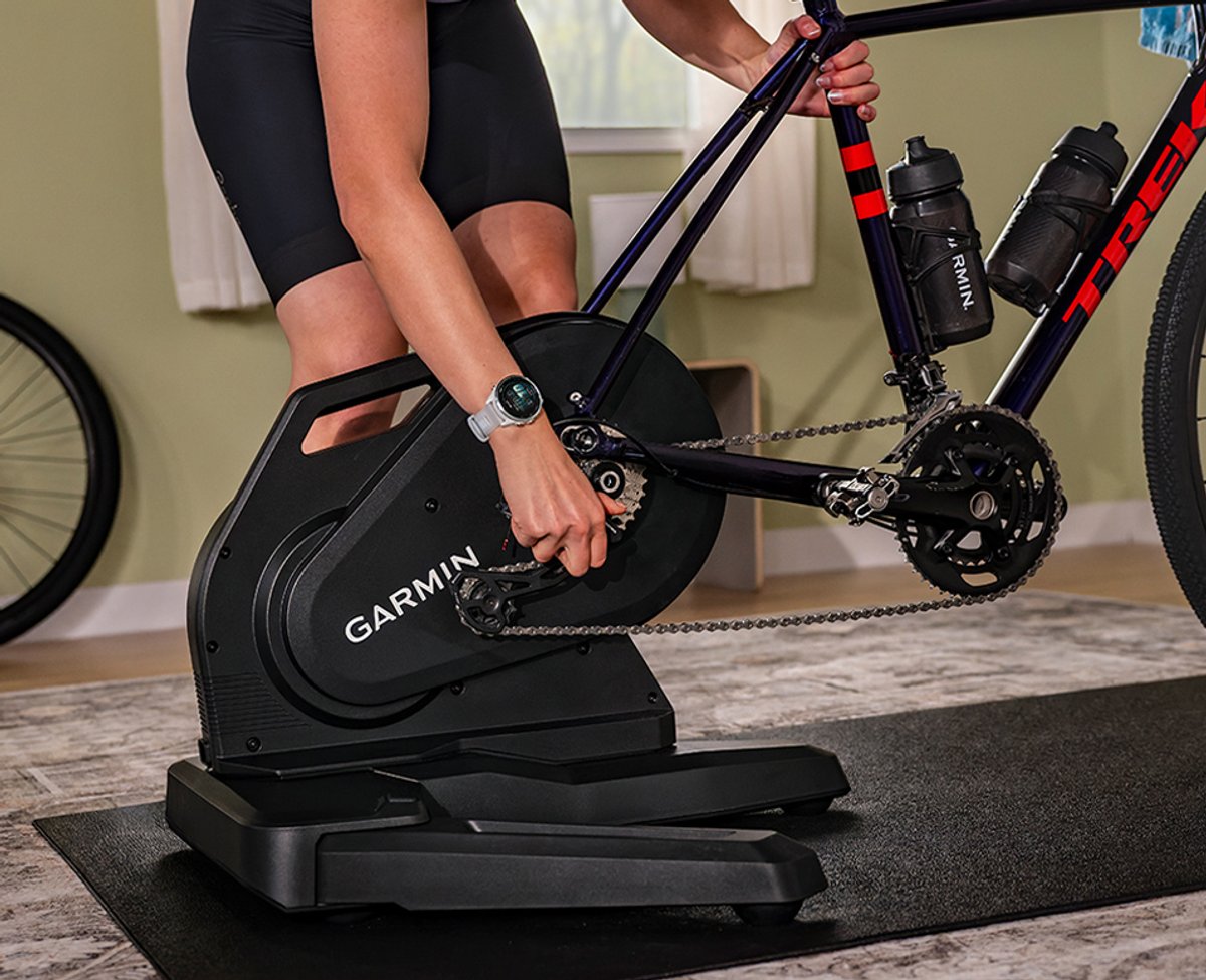 A person reaches down to adjust the Garmin Tacx Nera Trainer.