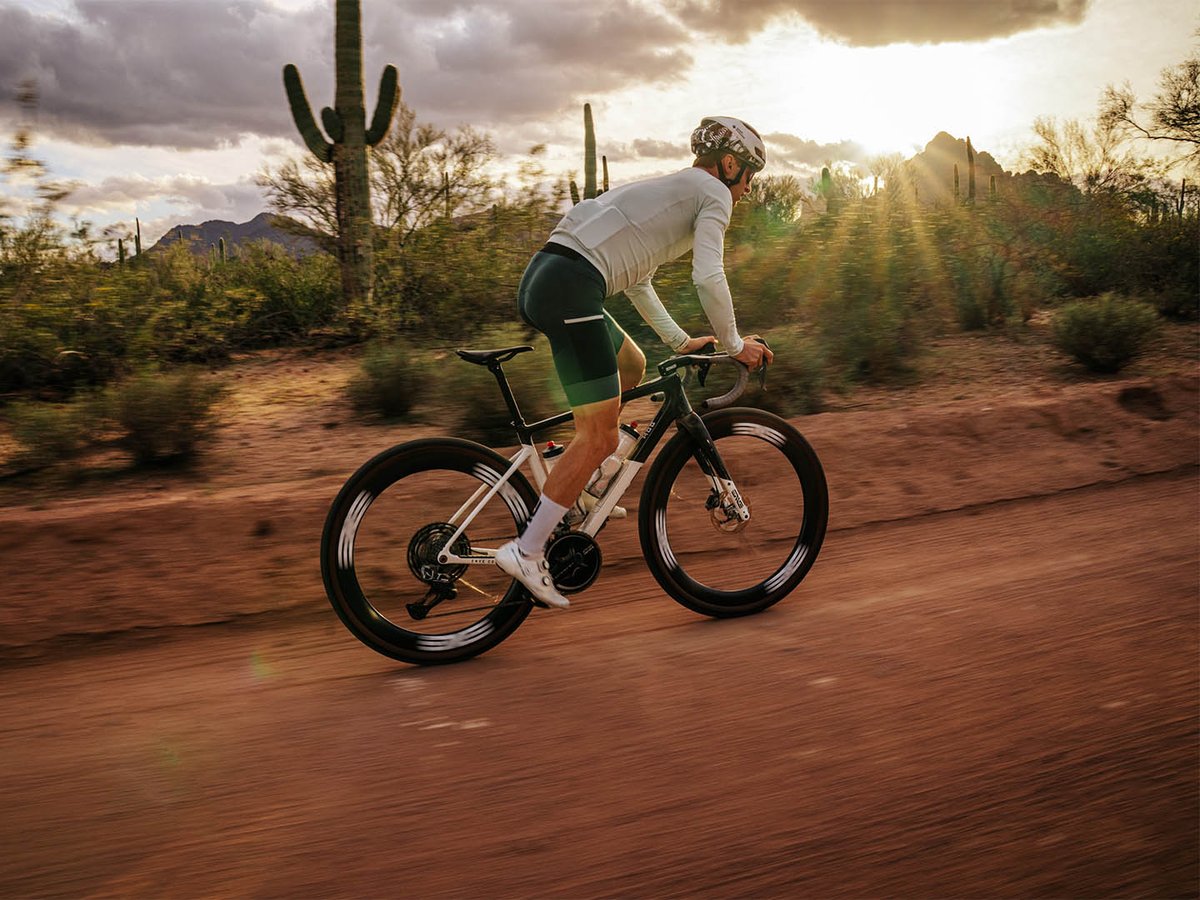 Gravel rider pedaling fast on dirt road in the desert.