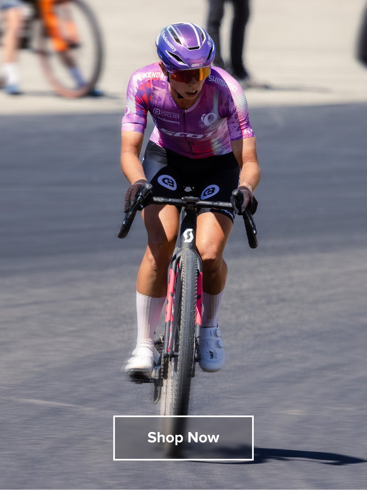 Hannah riding a gravel bike in a matching purple jersey and helmet.