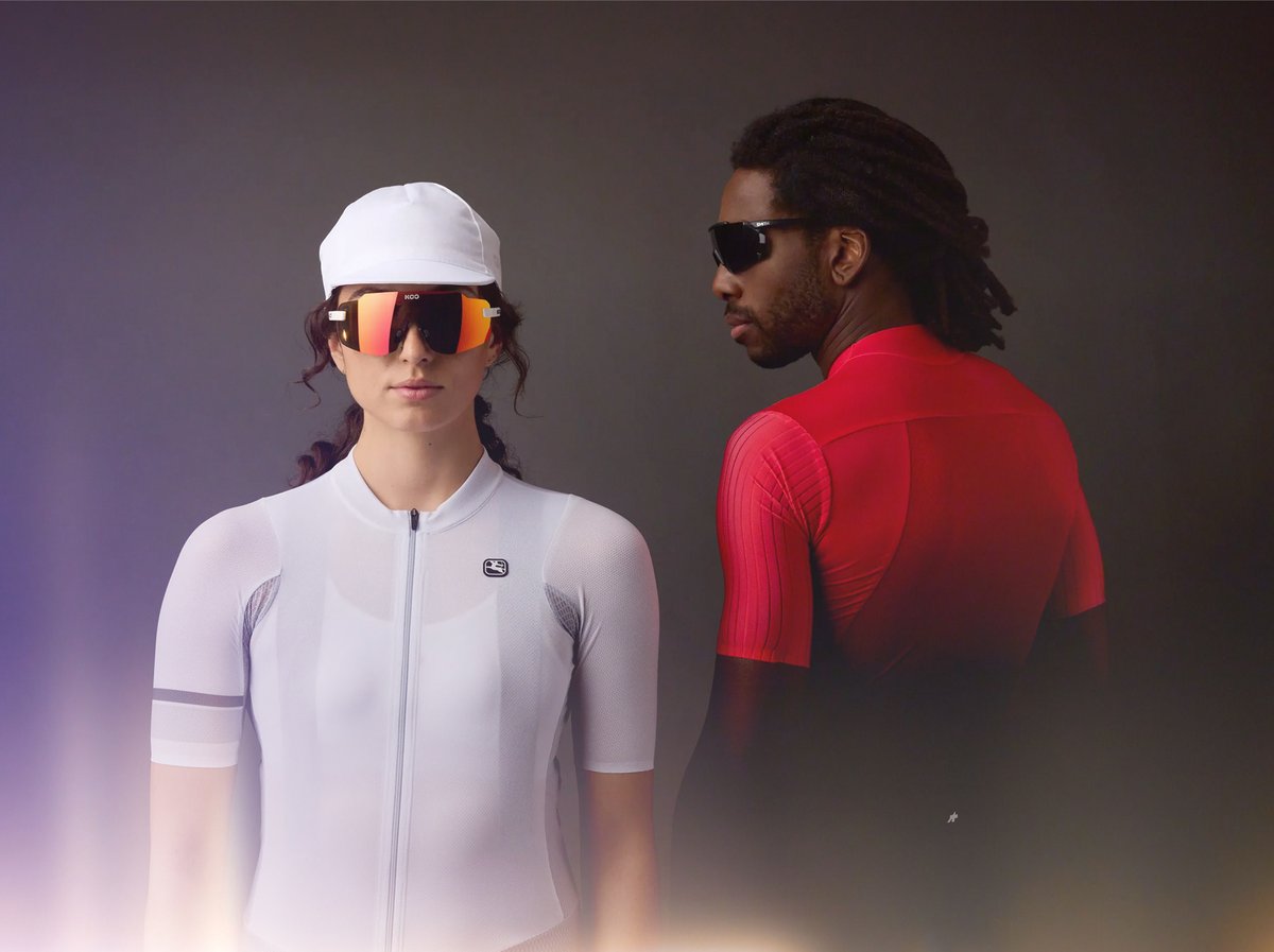 Promotional graphic for a Fourth of July sale featuring two cyclists riding on a scenic gravel road through rolling hills. A bold overlay reads, "Up to 50% Off" 